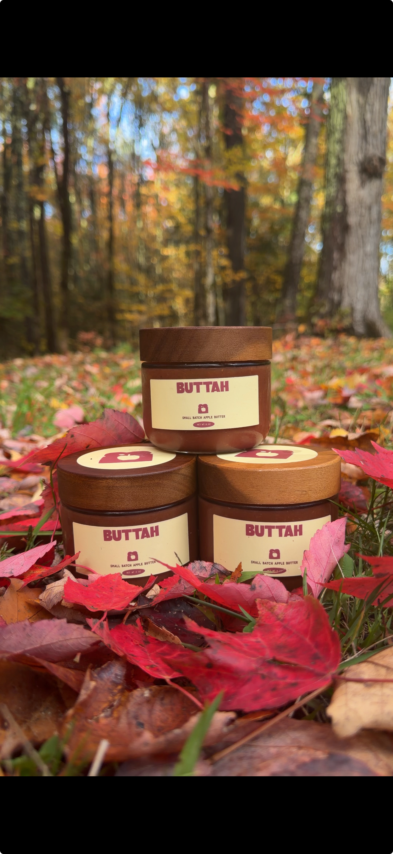 Three Buttah apple butter jars among red autumn leaves